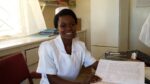 Audrey Mwaba, a registered nurse at a USAID ASSIST-supported health clinic and member of an improvement team, shows the improvements made in patients’ nutrition status record keeping. Photo by Elizabeth Silva, WI-HER LLC.